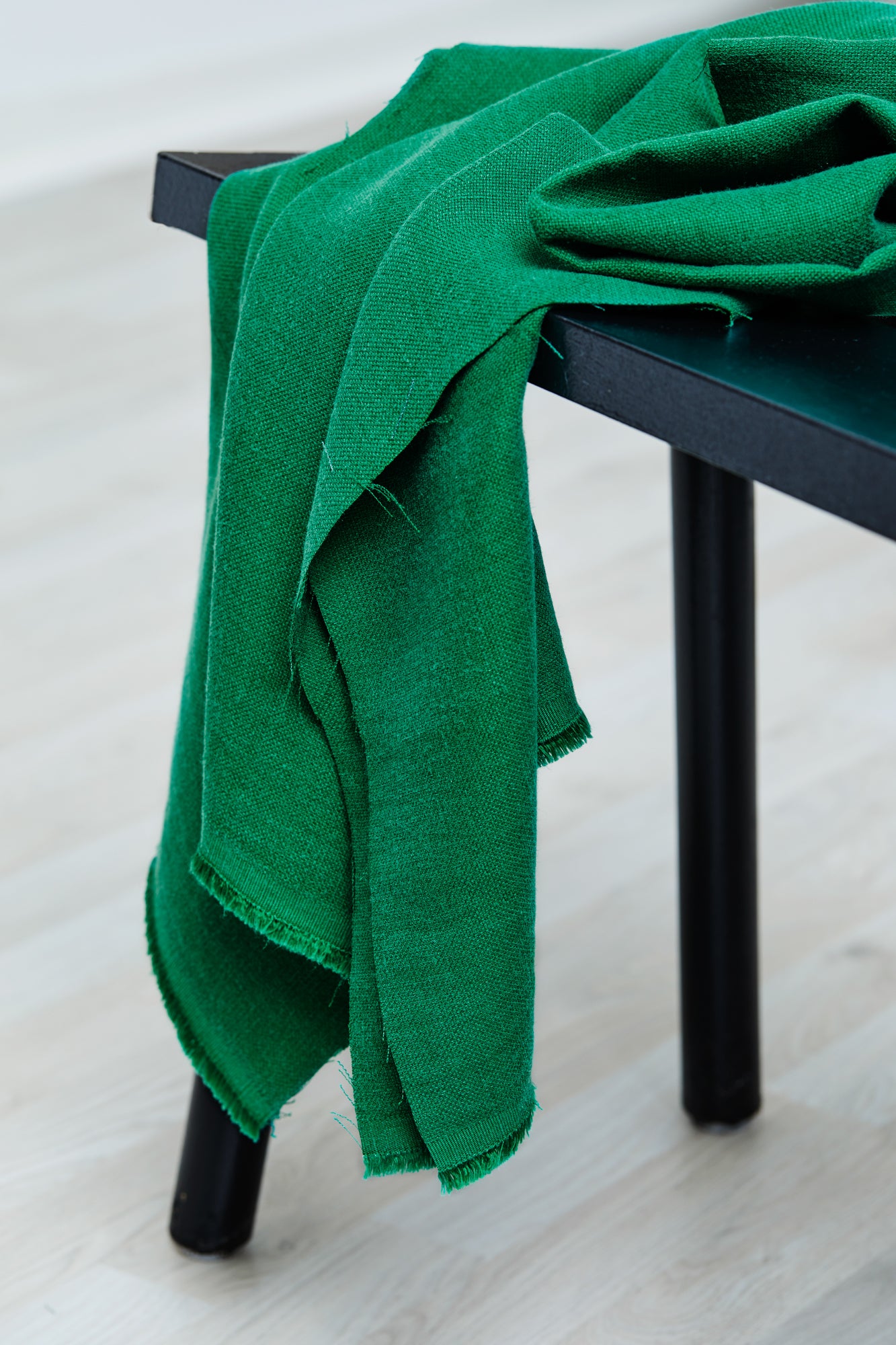 Mara linen blend tencel sewing fabric in colour frog green, draped over stool