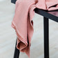 Mara linen blend tencel sewing fabric in colour puff (pink), draped over stool