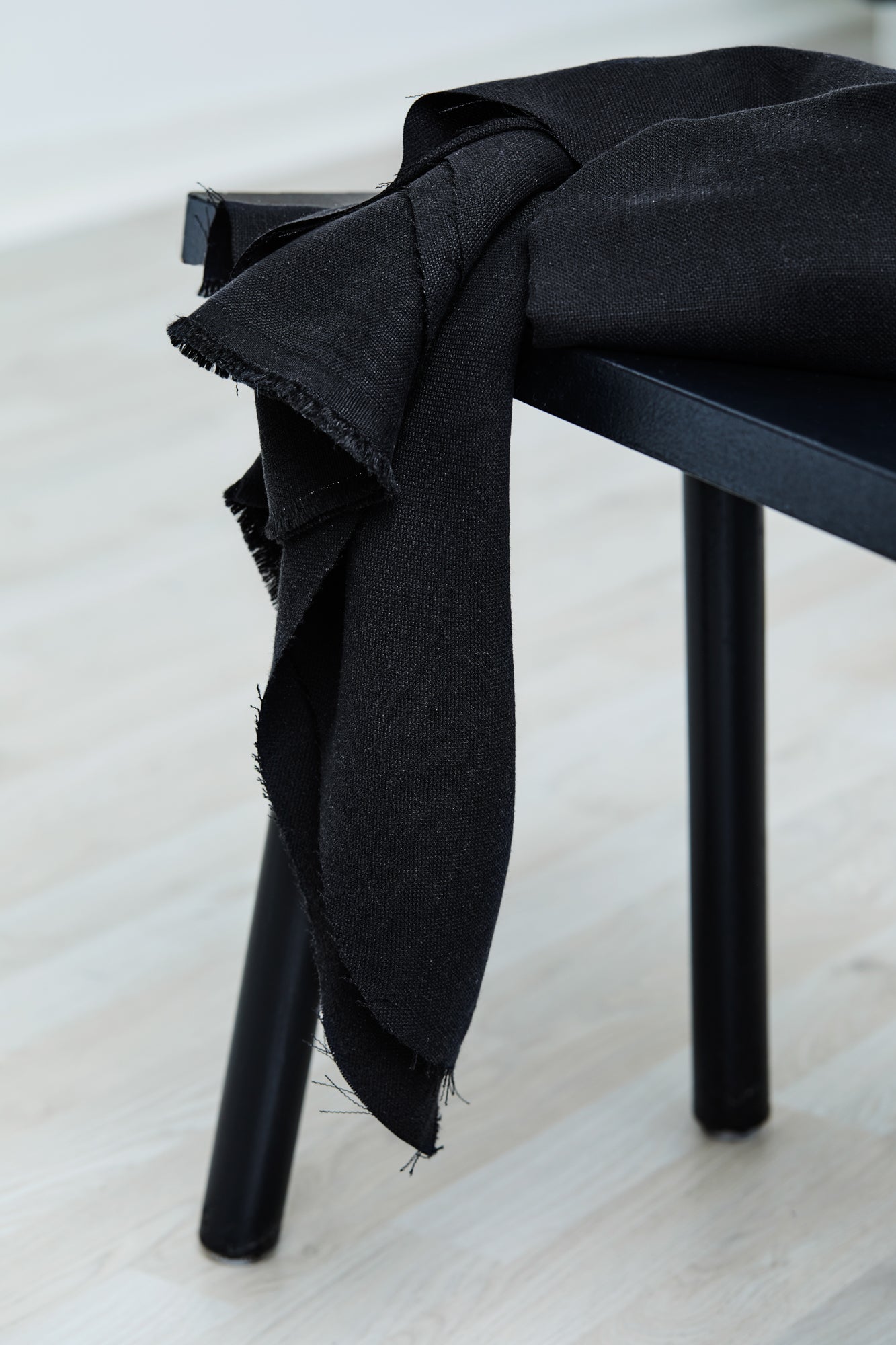 Mara linen blend tencel sewing fabric in colour black, draped over stool