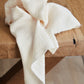 Organic cotton double guaze sewing fabric in colour creamy white, draped over wooden table