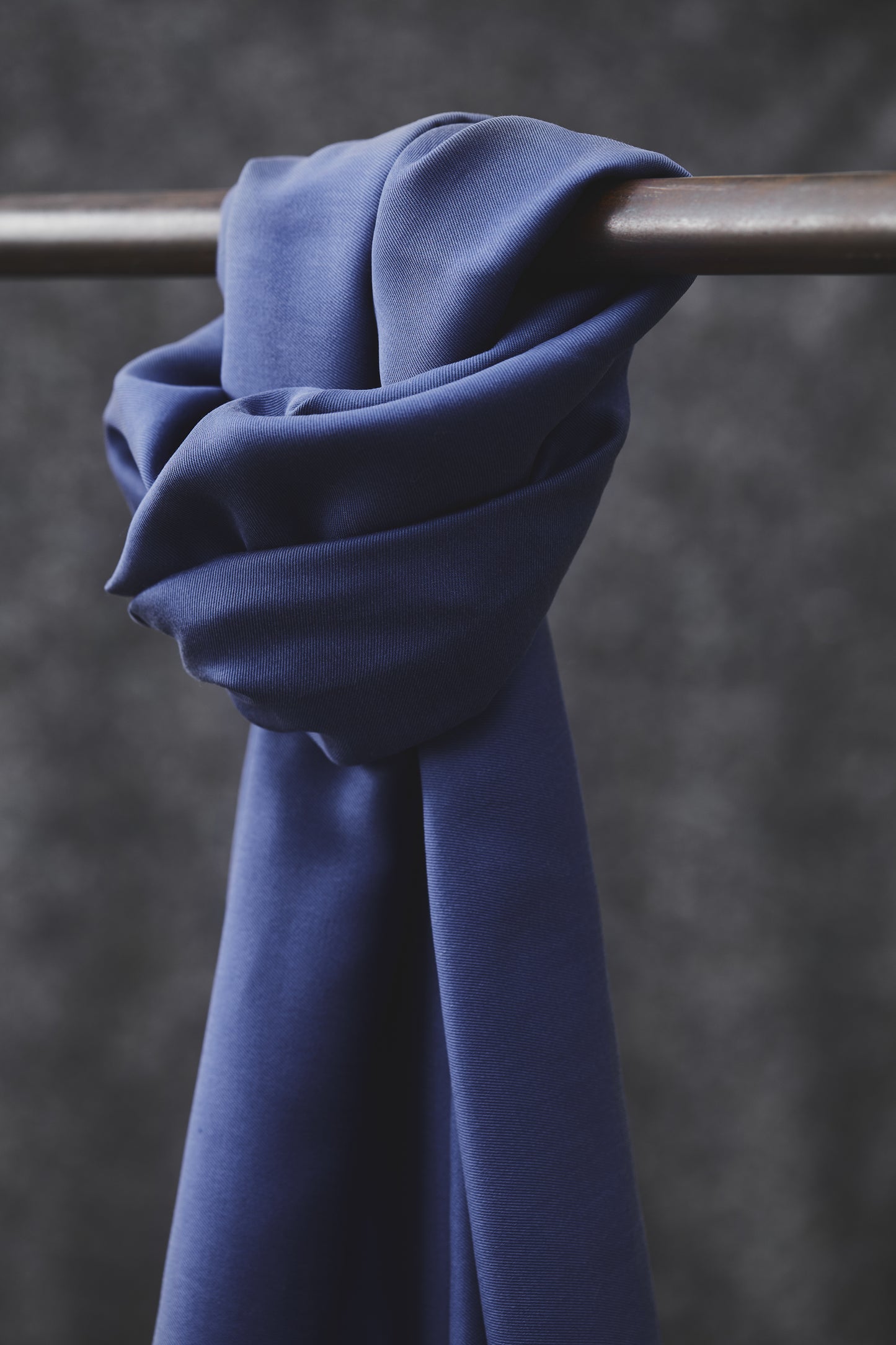Smooth drape twill tencel sewing fabric in lapis, knotted over clothes rail