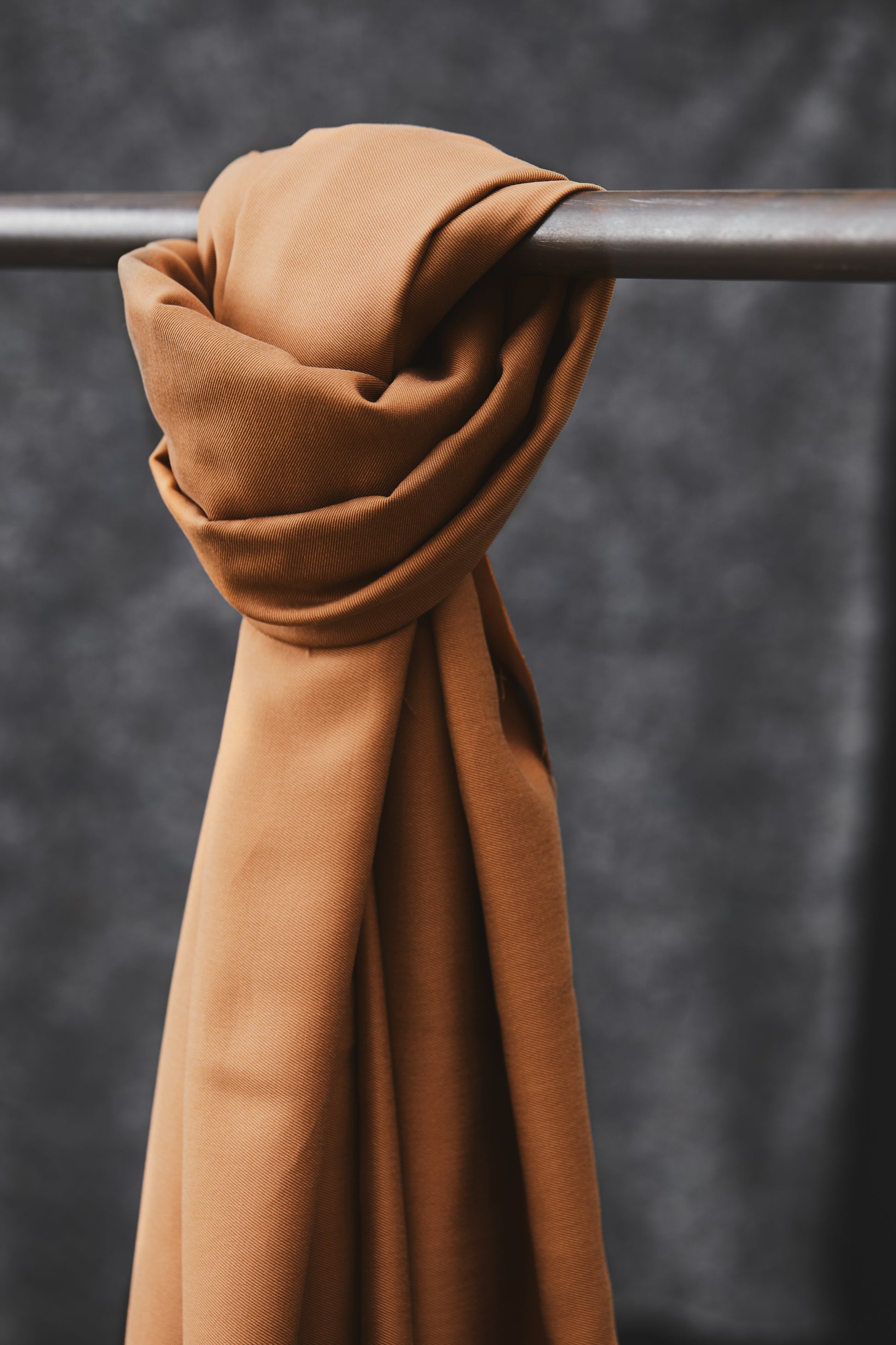 Smooth drape twill tencel sewing fabric knotted over clothes rail, in colour mustard