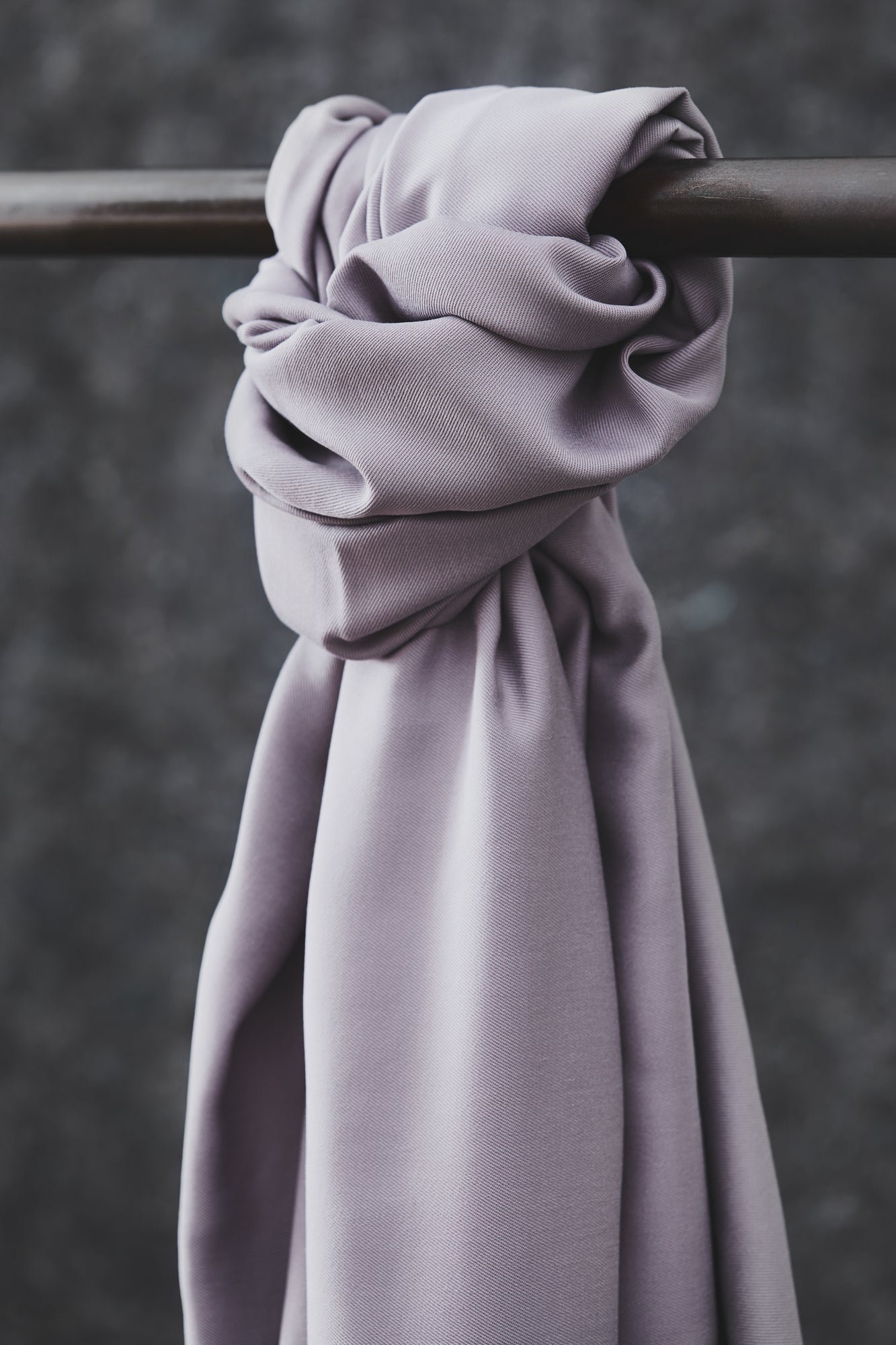 Smooth drape twill tencel sewing fabric knotted over clothes rail, in colour purple haze (lilac)