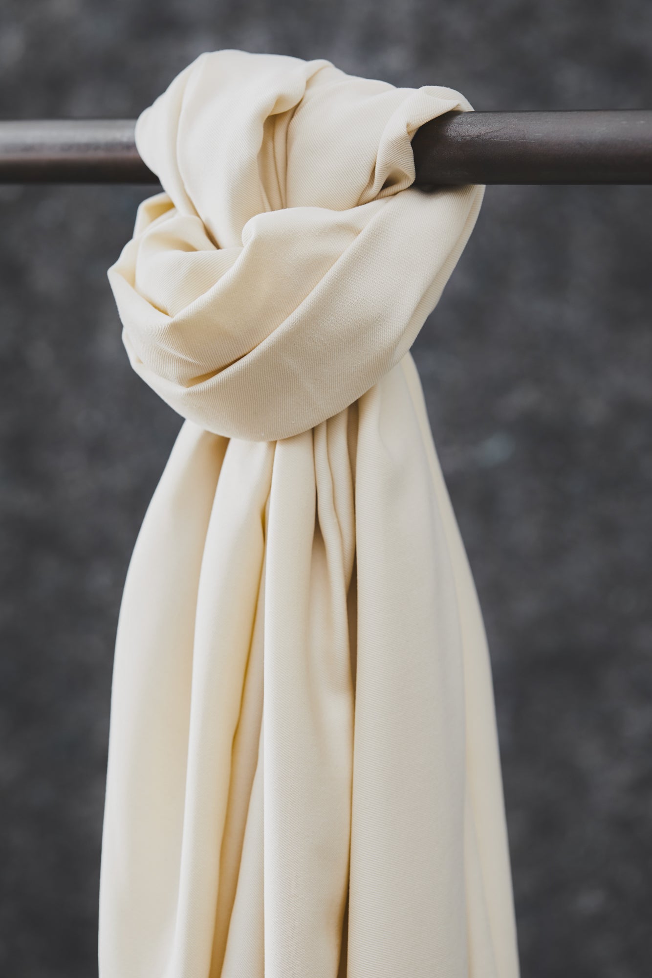 Smooth drape twill tencel sewing fabric knotted over clothes rail, in colour shell (cream)
