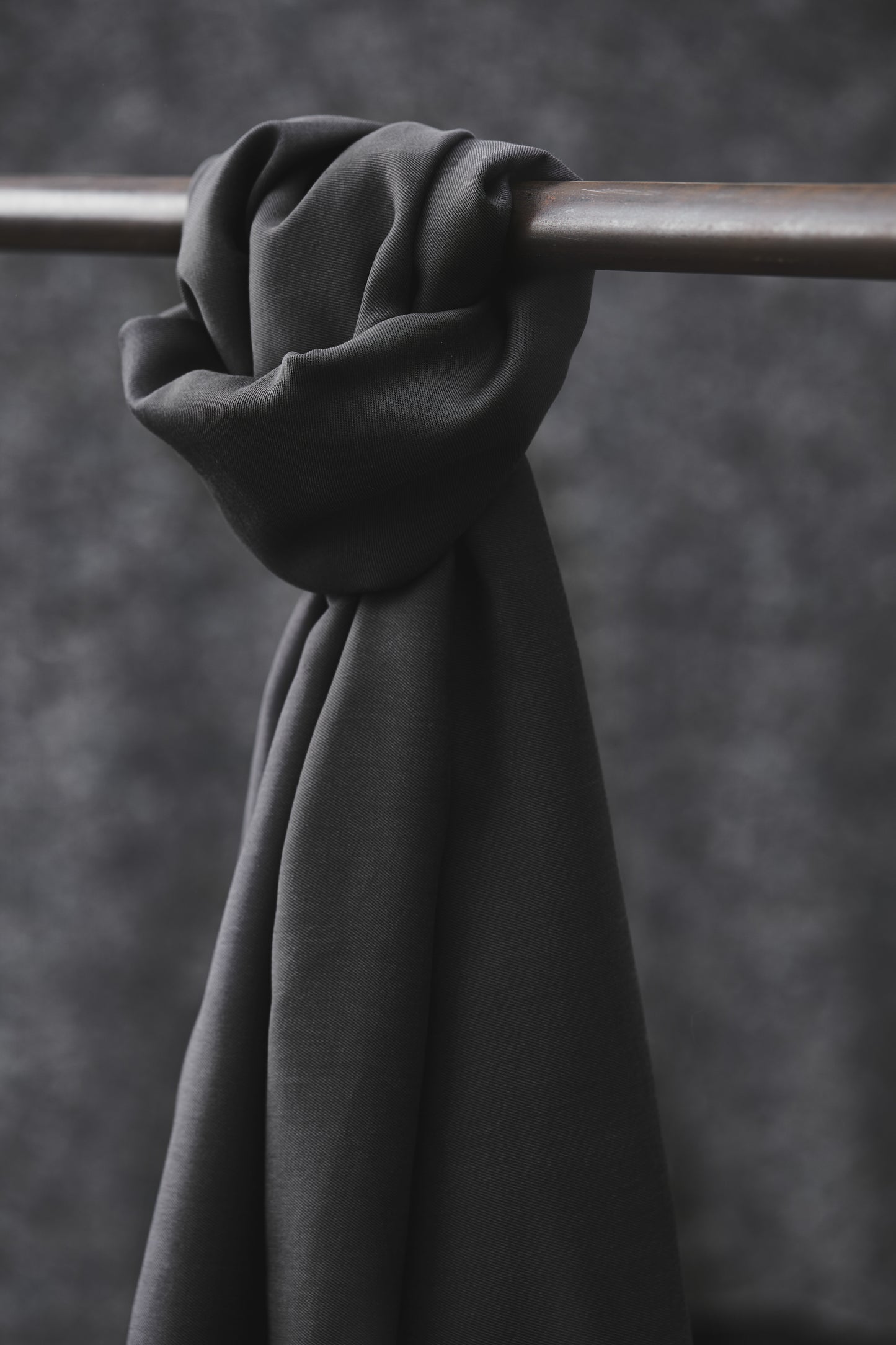 Smooth drape twill sewing fabric in grey knotted over a clothes rail