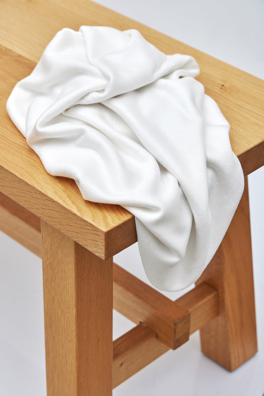 White Ecovero knit sewing fabric draped over wooden bench