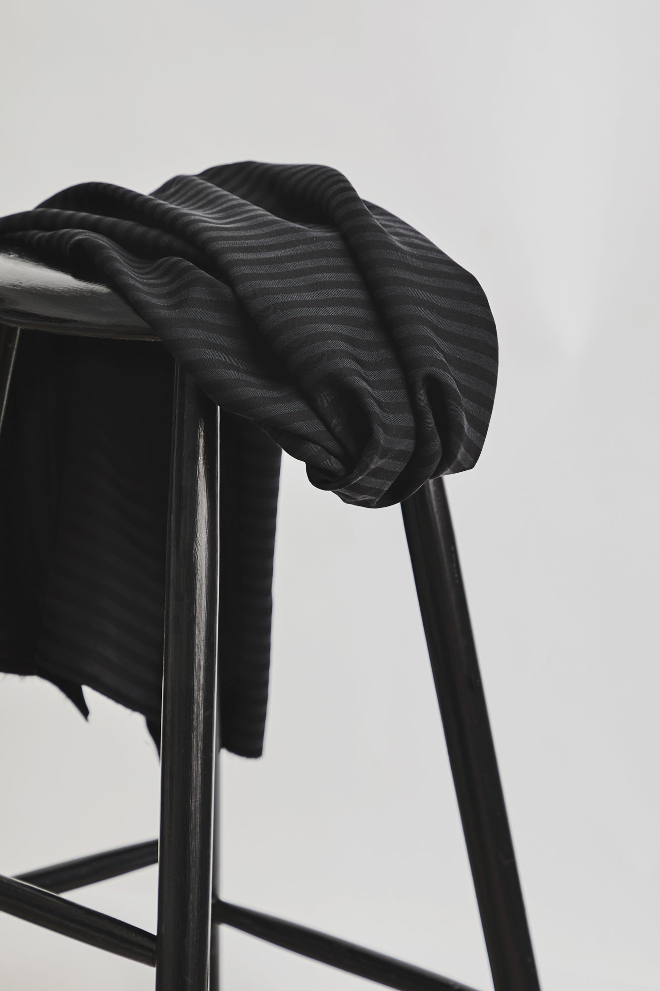 Sustainable tencel™ woven striped dressmaking fabric in black draped over stool