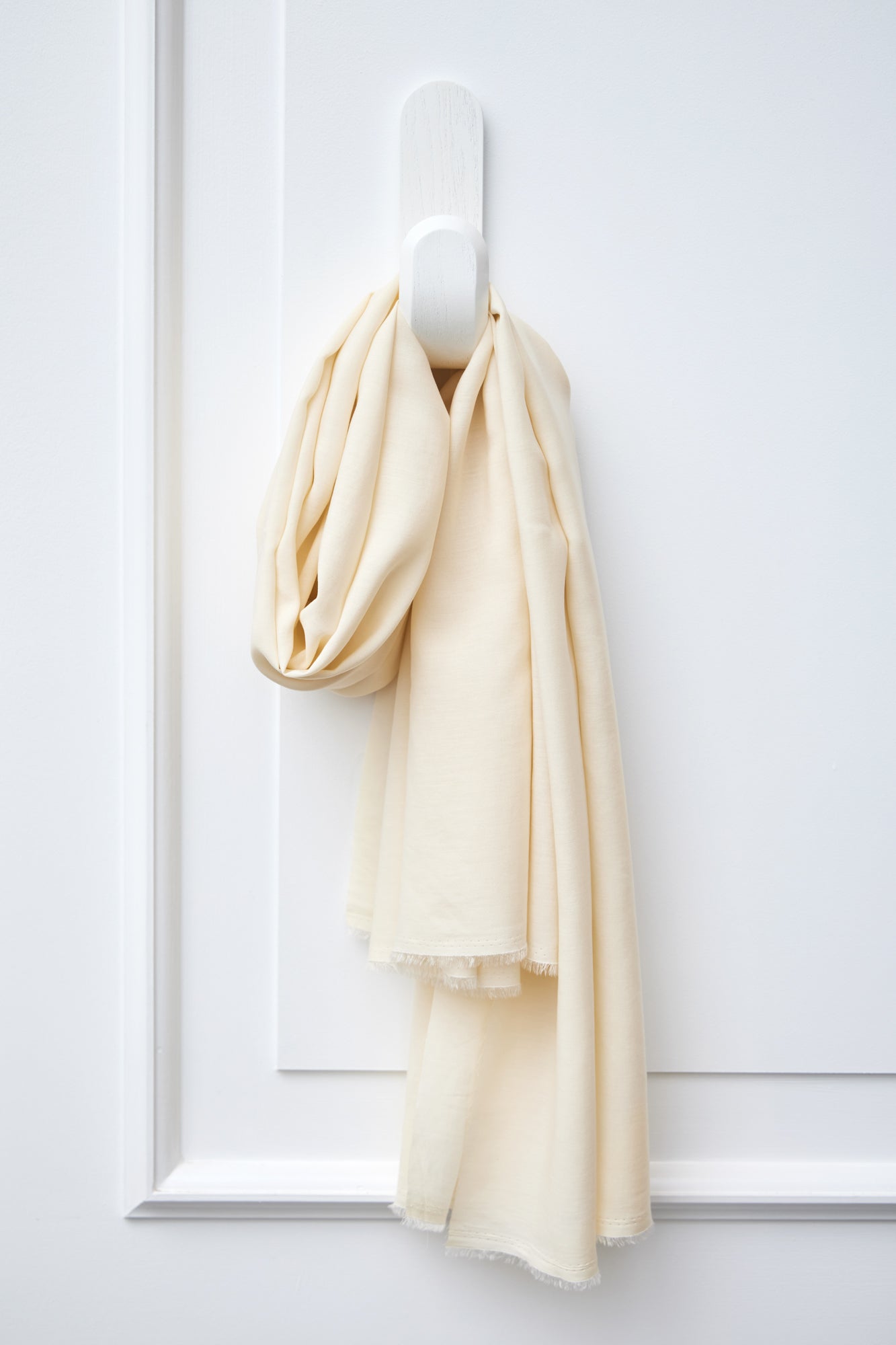 Piece of Vida voile tencel sewing fabric in colour shell (cream) hanging on white hook