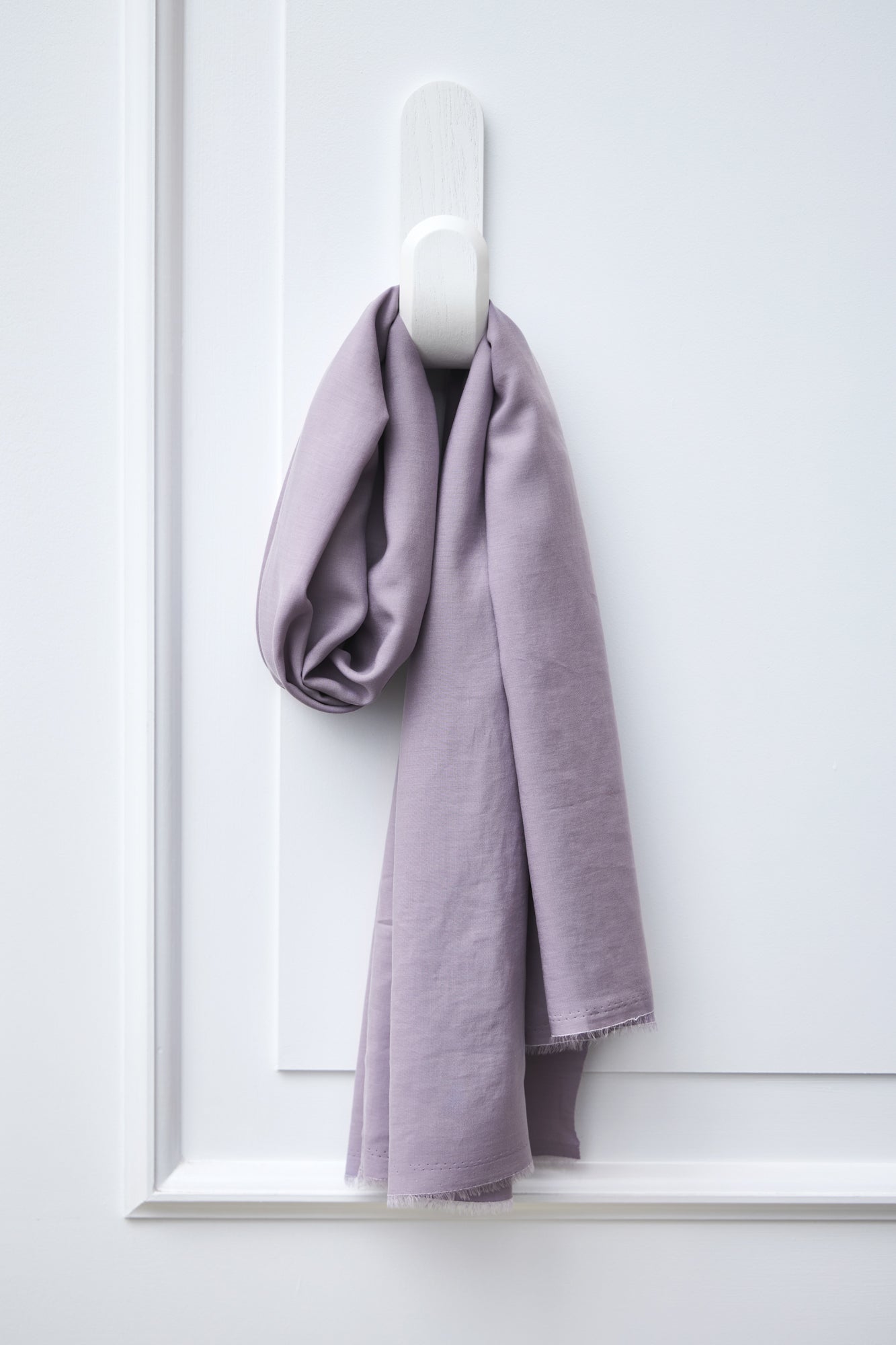 Piece of Vida voile tencel sewing fabric in colour purple haze, hanging on white hook